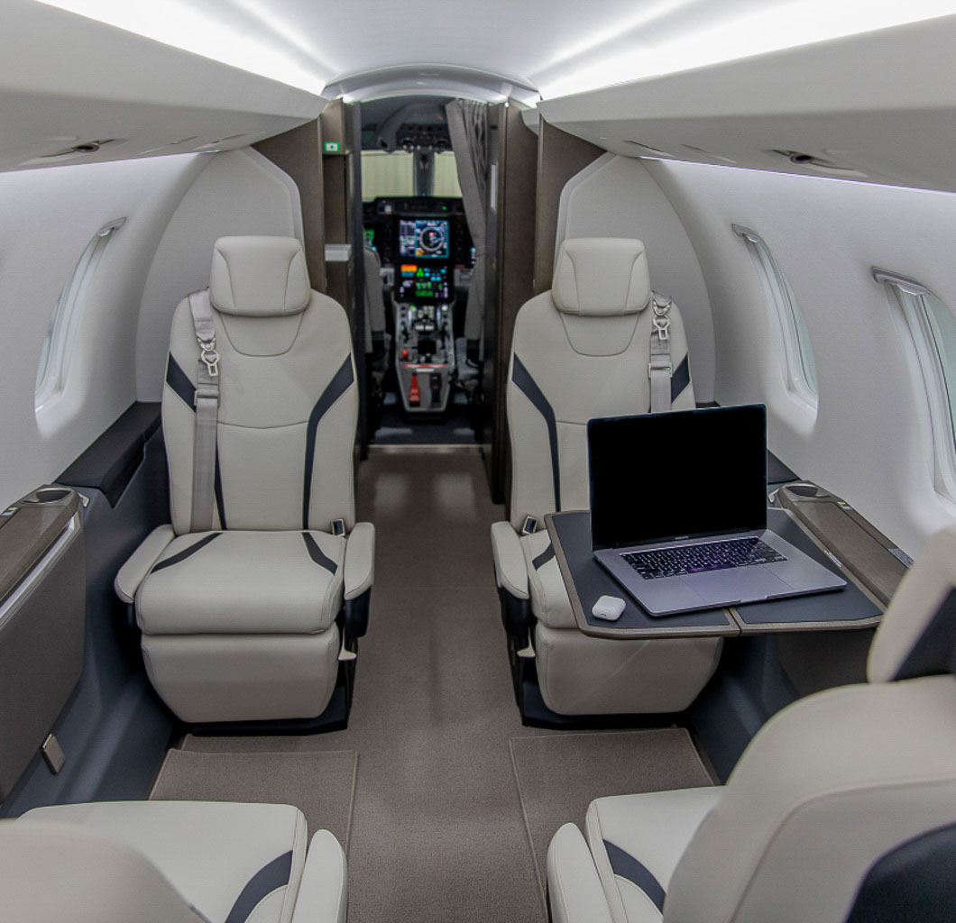 An interior of a private jet with seats and a view of the cockpit